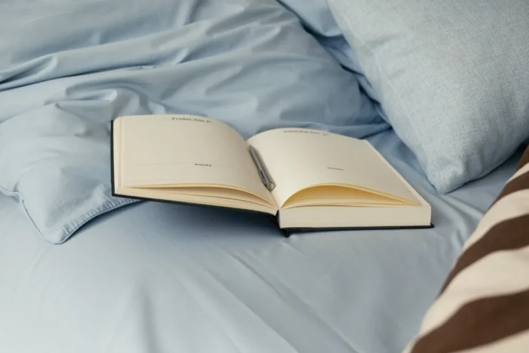 دفترچه‌ی باز و سفید روی ملافه‌ی آبی